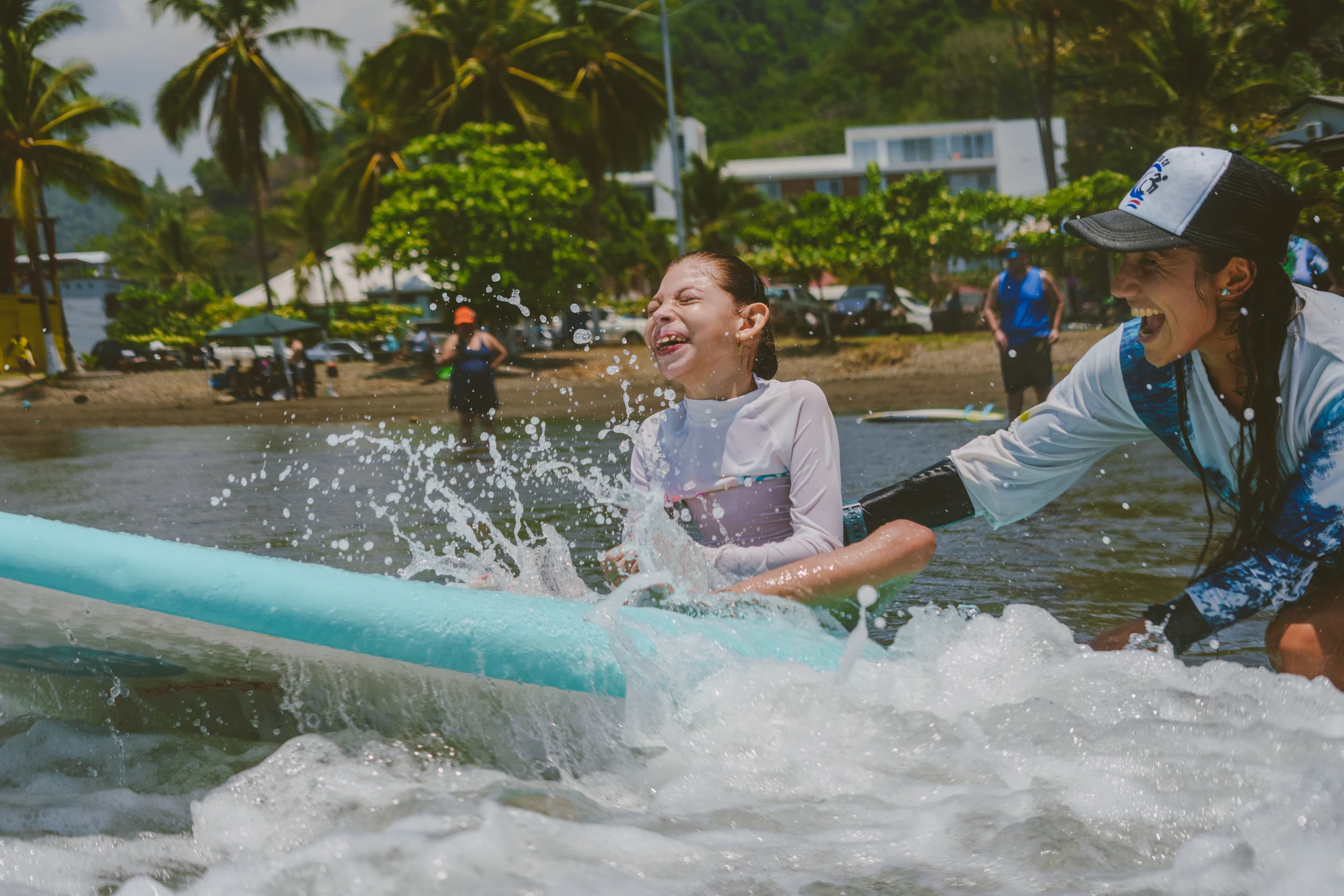 Niña con parálisis cerebral entrando al mar con instructora de surf