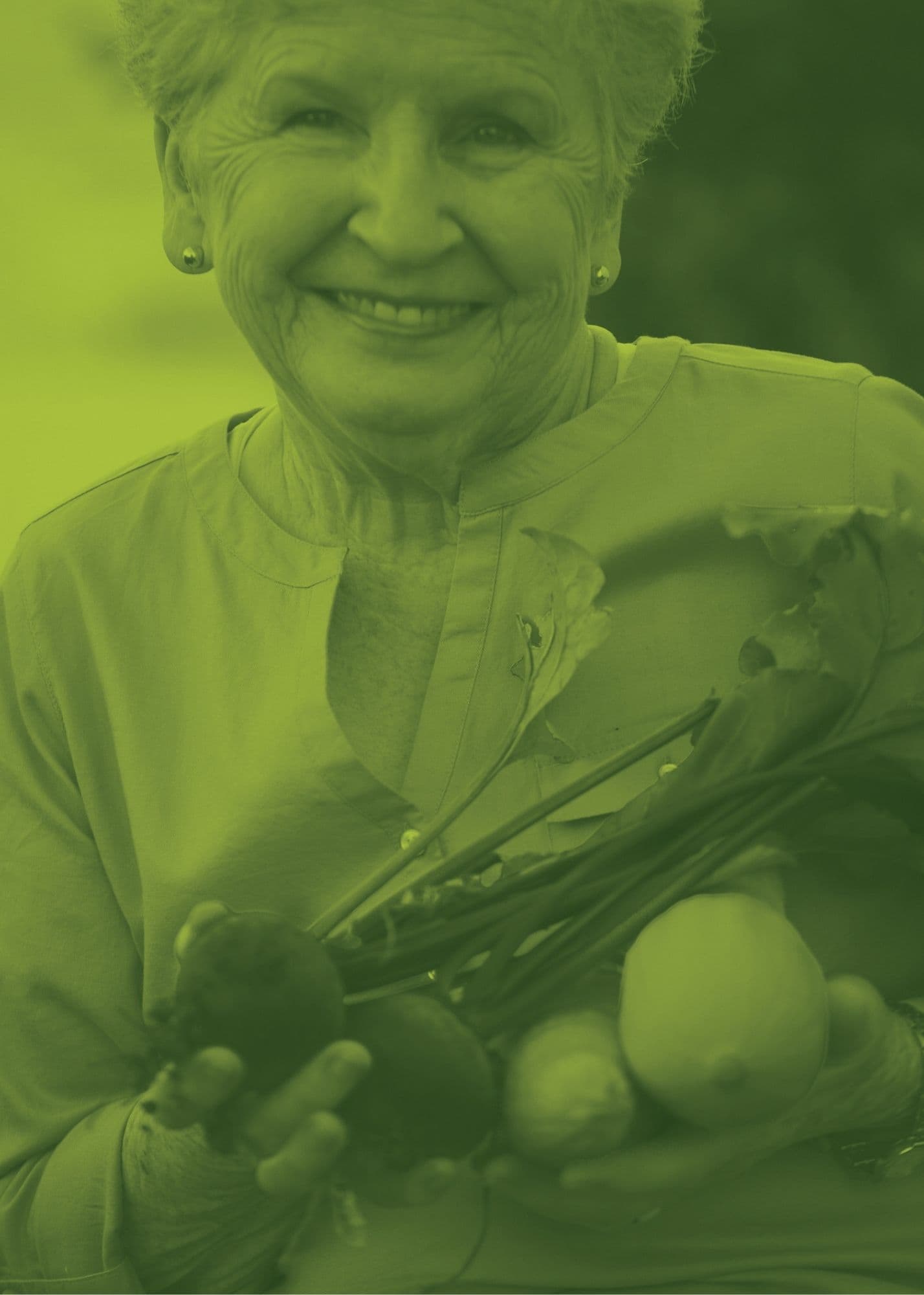 A smiling woman holding a variety of fresh produce 