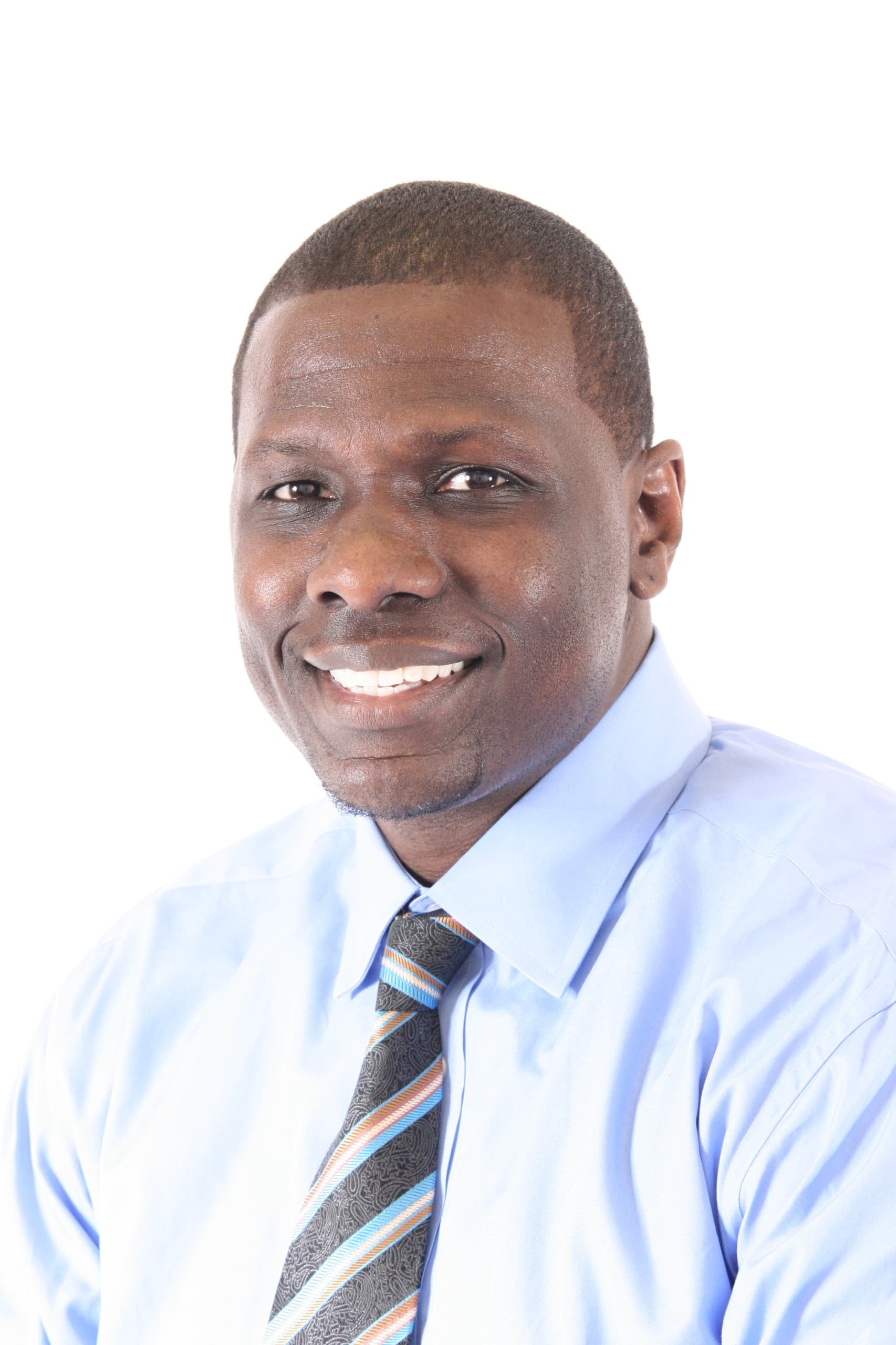 Willie Brake displaying a beautiful smile with a clean crispy haircut wearing a blue dress shirt and a gray striped tie