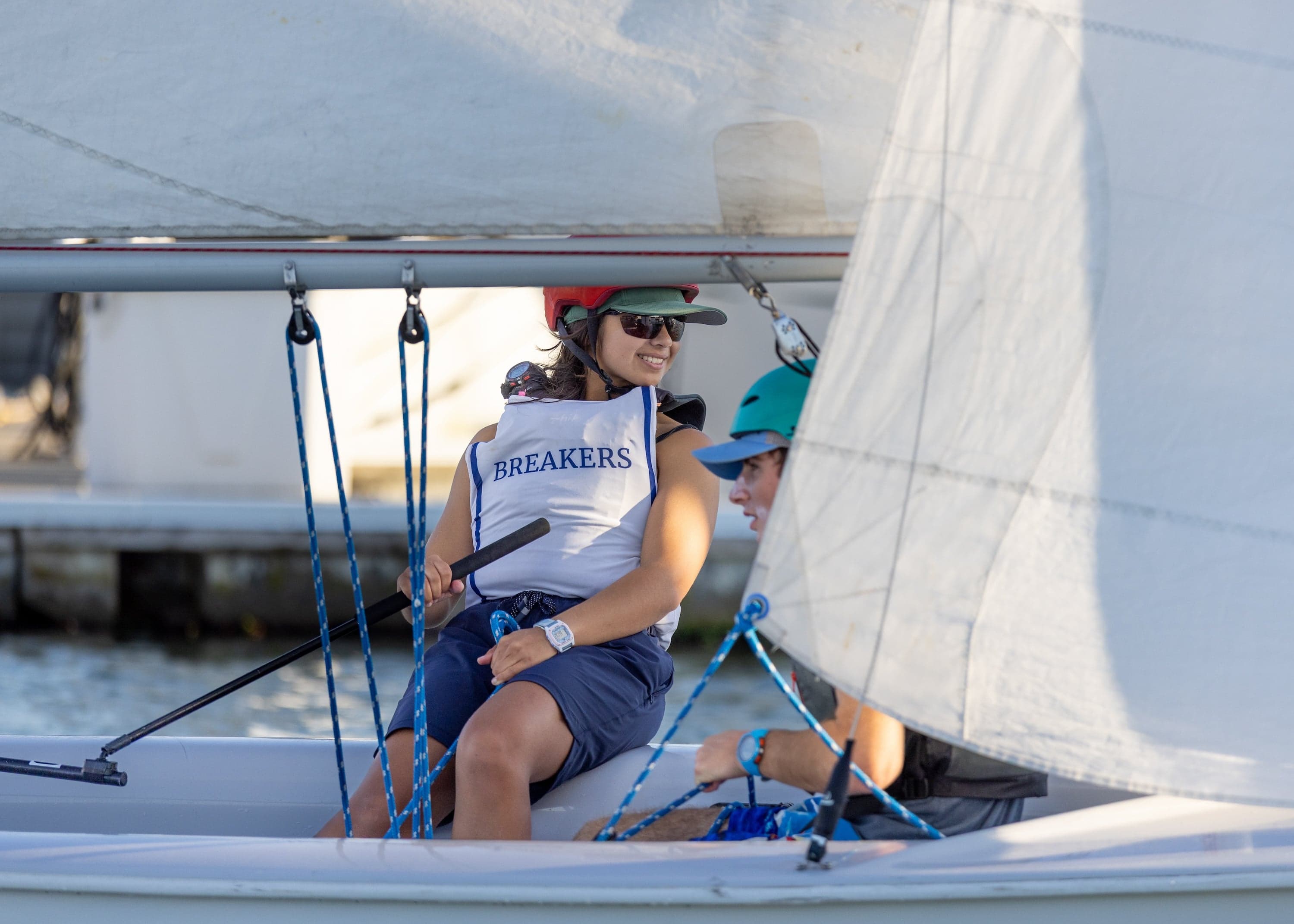 a student in a Bay Breakers life vest sits on the edge of a sailboat