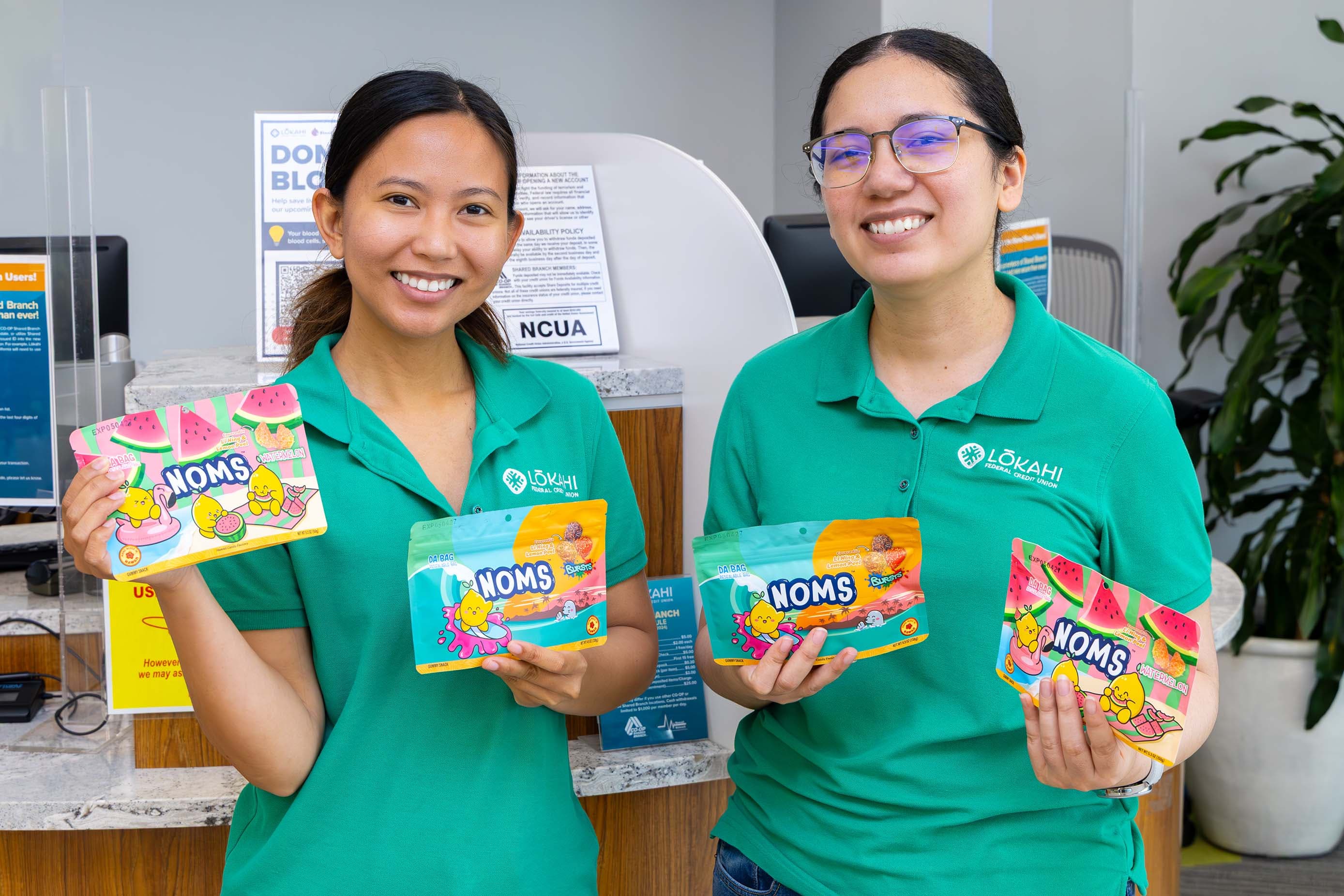 Two Lōkahi FCU staff members holding FUNDRAISING bags of NOMS